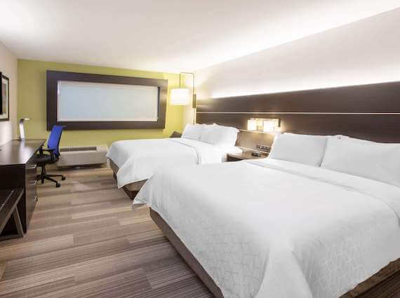 Hotel guest room with beds in front of roller shades